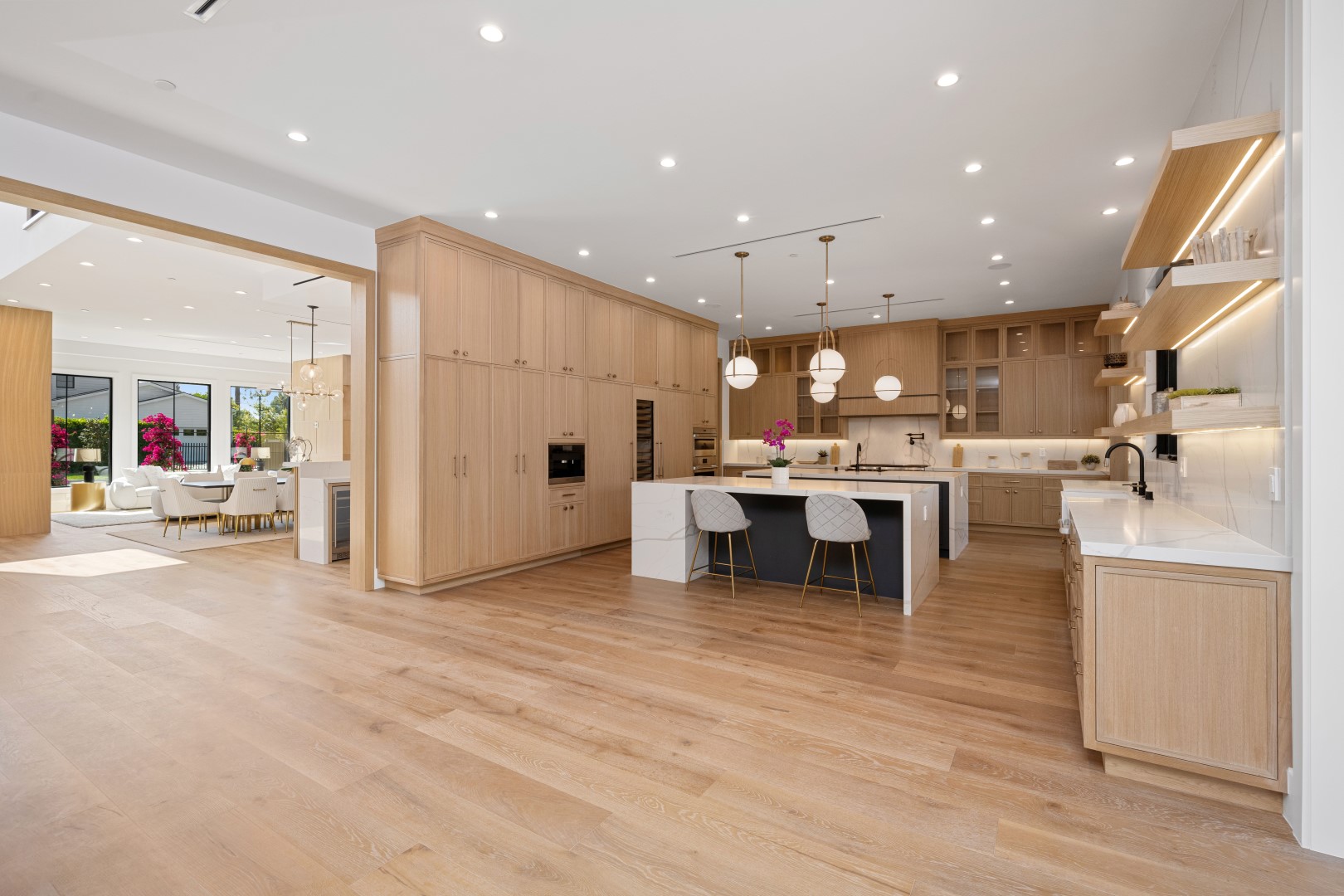 Modern luxury kitchen with light wood cabinetry and large island.