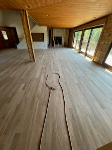 A spacious room with warm wood floors, complemented by a garden hose placed strategically in the corner for easy access.