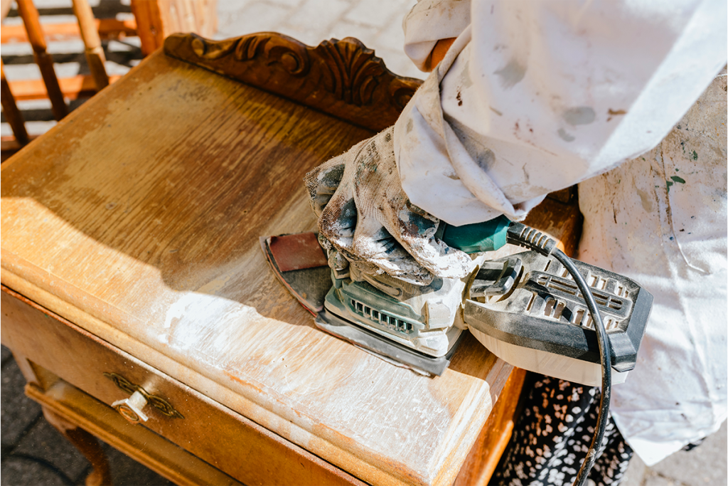 someone sanding a piece of furniture